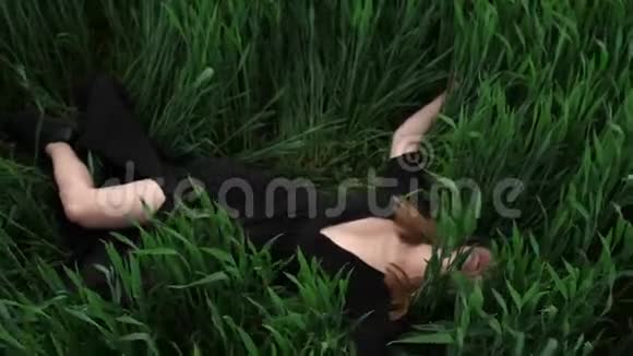 穿黑色衣服的女孩在草地上撒谎视频的预览图