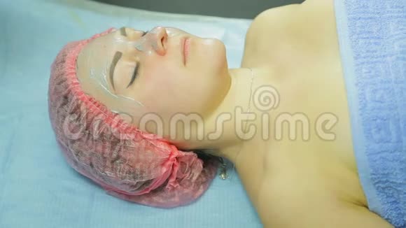 戴手套的美容师用刷子把泥面罩涂在女人脸上侧视图视频的预览图