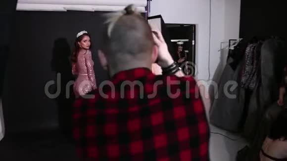 摄影棚里的摄影师模特棕色头发穿着粉红色的裙子视频的预览图