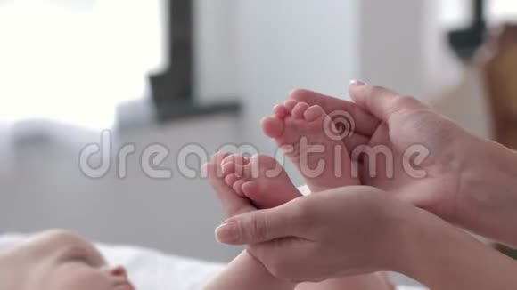 幼小的新生婴儿双脚在妈妈的关怀之手中紧紧地抱着小女孩正积极地趴在换衣桌上视频的预览图