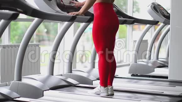 女人在健身俱乐部跑步机上慢跑在健身房跑步的女性视频的预览图