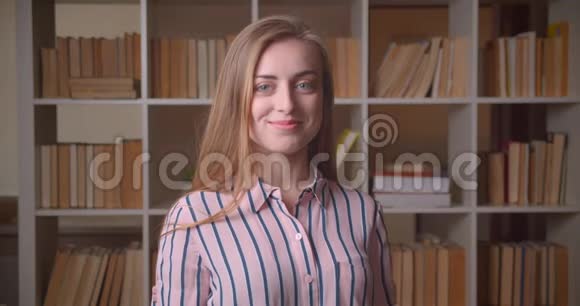 一幅年轻快乐的白种人女学生的特写照片她兴奋地笑着看着学院里的摄像机视频的预览图