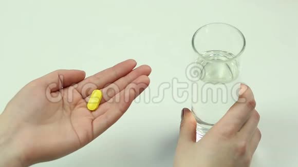 患有头痛或发烧的妇女吃药喝一杯水视频的预览图