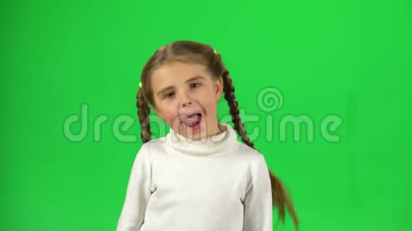 可爱的女孩在玩做有趣的脸在绿色屏幕上显示舌头视频的预览图