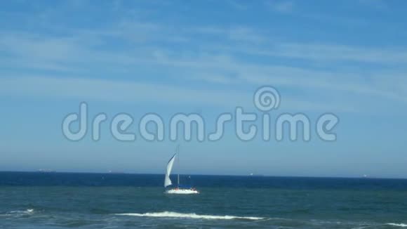 帆船在海面上晴朗的天气天空上有几片白云背景帆船在靠近海岸的蓝海中航行视频的预览图