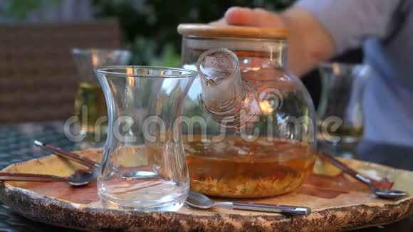 一个人把热茶从玻璃茶壶倒入一个透明的杯子里草药茶视频的预览图