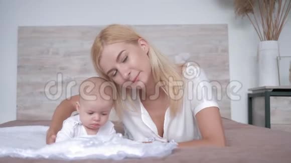 母爱年轻的父母亲吻新生的女婴看着躺在床上的镜头视频的预览图