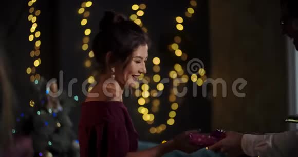 幸福微笑的年轻女性穿着红色时尚服装的肖像女孩收到生日礼物和新年礼物圣诞节视频的预览图