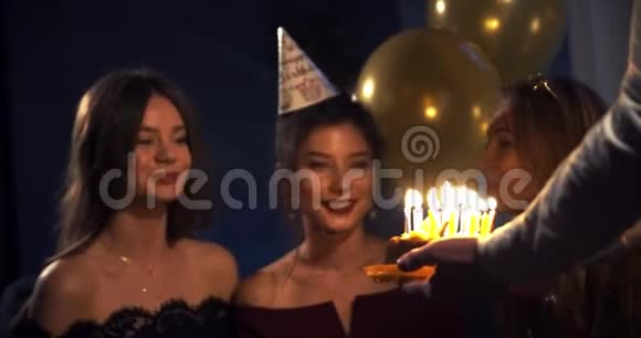 那个人给女孩带了一个生日蛋糕她吹灭了聚会上被朋友包围的蜡烛一幅肖像画视频的预览图