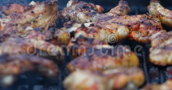 靠近美味的烤鸡肉翅在烧烤架上翻转视频的预览图