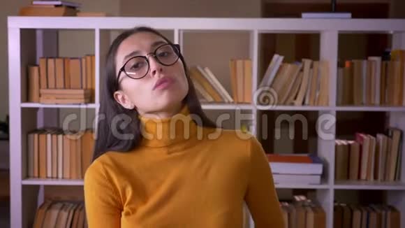 一幅漂亮的黑发女教师戴着眼镜摆成相机在图书馆里调情视频的预览图