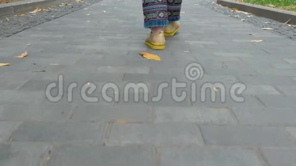 女腿蓝色牛仔裤黄色鞋子沿着公园的小路走视频的预览图