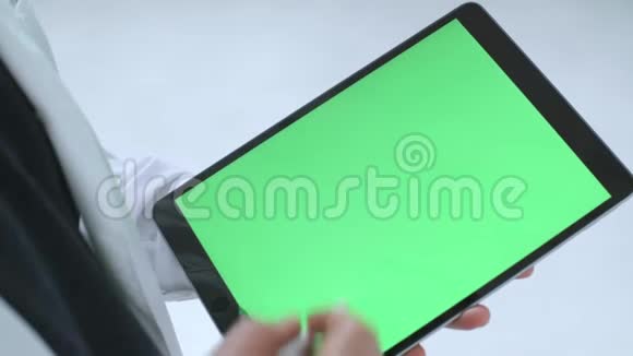 白色医生的人的特写镜头他的外套和黑色衬衫在平板电脑上敲击铬键绿色屏幕股票视频的预览图
