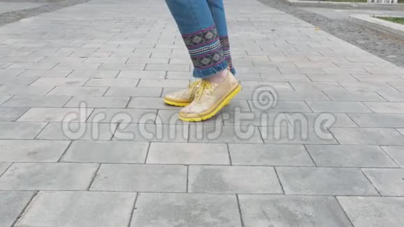 秋天公园里女腿蓝色牛仔裤黄色靴子沿着人行道视频的预览图
