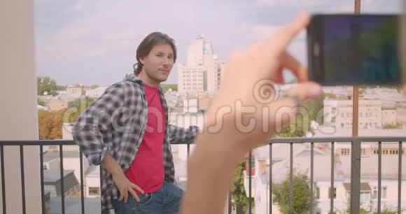 白种人成年男子的特写站在房子的阳台上通过电话拍照的特写照片视频的预览图