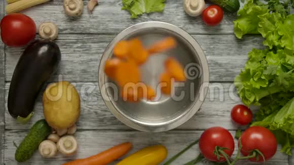 胡萝卜片落在装有水的金属碗里视频的预览图