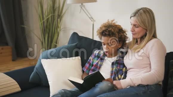 妈妈和儿子坐在舒适的沙发上看书视频的预览图