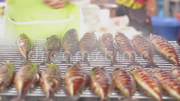 泰国当地食品市场的一位男厨师在木炭烤架上烤鱼视频的预览图