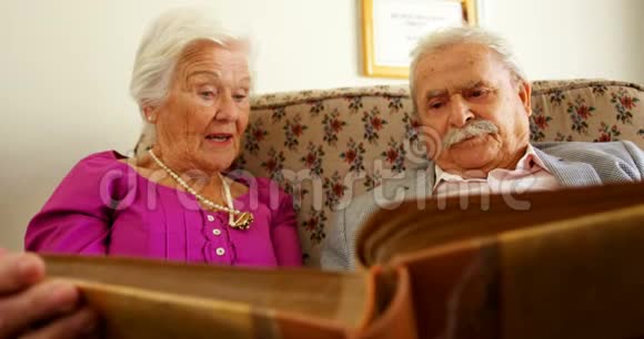积极的高加索老年夫妇在养老院观看相册的正面视图视频的预览图