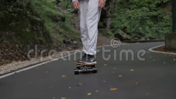 滑雪腿在蜿蜒的山路上骑着滑板穿过山林视频的预览图