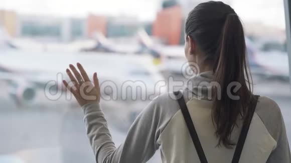 在飞机背景下带背包的女孩在机场向外望窗的近景视频的预览图
