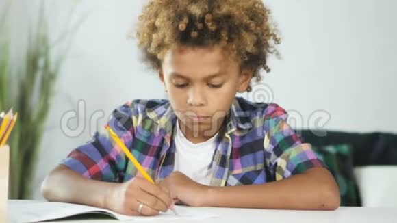 非裔美国小男孩坐在餐桌前做学校作业视频的预览图