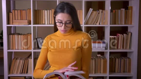 在图书馆聚精会神地看眼镜书的漂亮黑发老师的画像视频的预览图