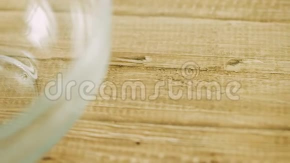 大块融化的巧克力倒入木桌上透明的碗里视频的预览图
