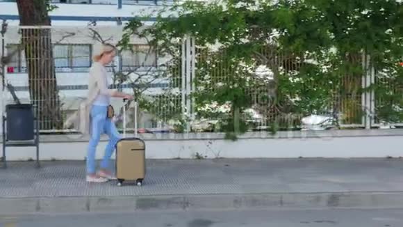 stadicam镜头带着行李箱的年轻女人在马路上西班牙度假胜地概念抵达视频的预览图