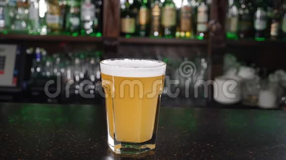 冰块掉进装满啤酒的杯子里慢动作泡沫和溅在酒吧柜台上营养和饮料概念视频的预览图