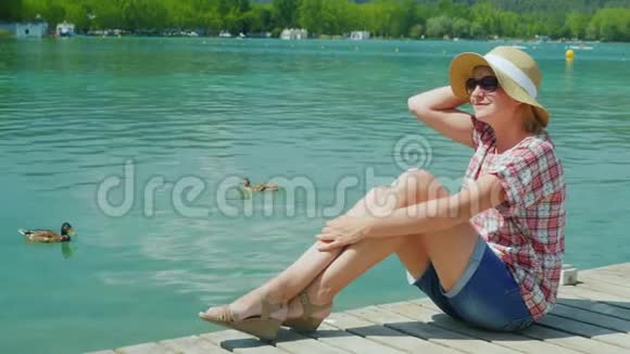 一位女游客在鸭子游泳的湖边度假西班牙度假村视频的预览图