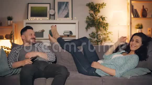 夫妻俩在家看电视上的搞笑电影一起笑着说话视频的预览图