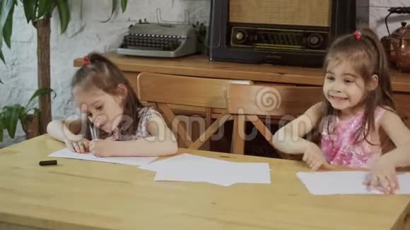 两个小女孩笑着在木桌旁画画视频的预览图