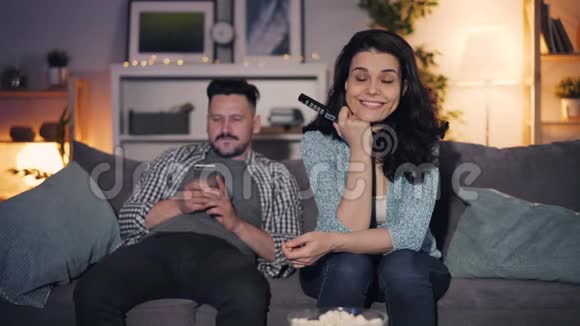 女孩和男人看电视讨论新闻谈话男人在家里使用智能手机视频的预览图