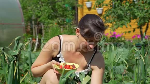 在花园里摘草莓的年轻女子视频的预览图