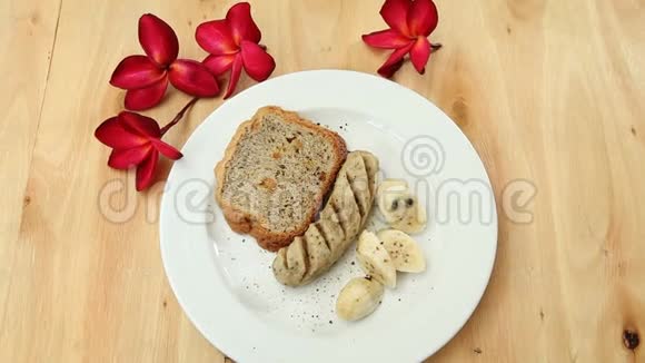 放在木桌上的白色盘子上的香肠面包香蕉视频的预览图