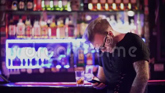 站在酒吧柜台边戴眼镜的漂亮胡子男用手机发短信视频的预览图