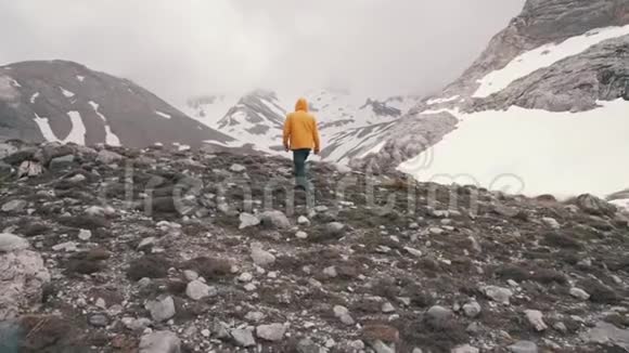 一个穿着黄色外套的人走在白雪覆盖的田野上视频的预览图