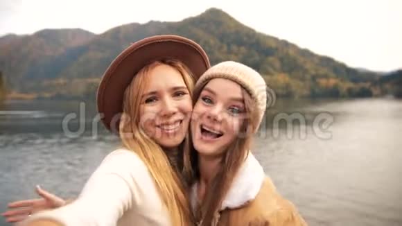 两个非常快乐迷人的女孩年轻的女人时髦地穿着度假的衣服在山上的一个湖上拍摄视频聊天视频的预览图