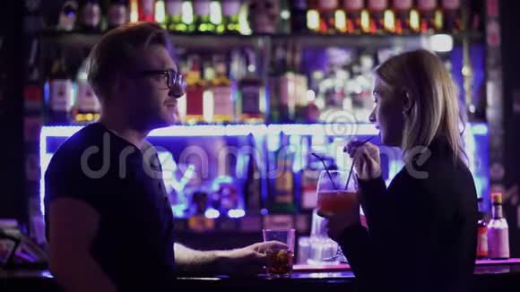 一个英俊的长胡子的家伙和一个可爱的年轻女人金发站在夜总会的酒吧柜台附近一男一女视频的预览图