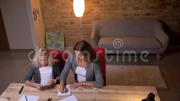 年轻的白种人母亲教她的小漂亮女孩并给她一个代数任务来解决问题视频的预览图
