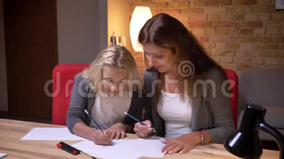 年轻母亲和她漂亮的小女儿在一张舒适的报纸上一起玩抽搐战术脚趾游戏的特写照片视频的预览图