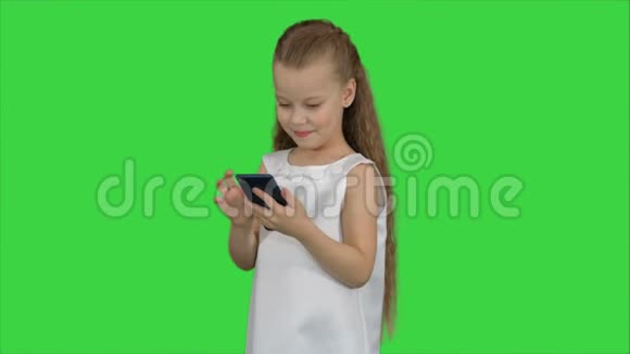 绿色屏幕上使用智能手机的小女孩Chroma键视频的预览图