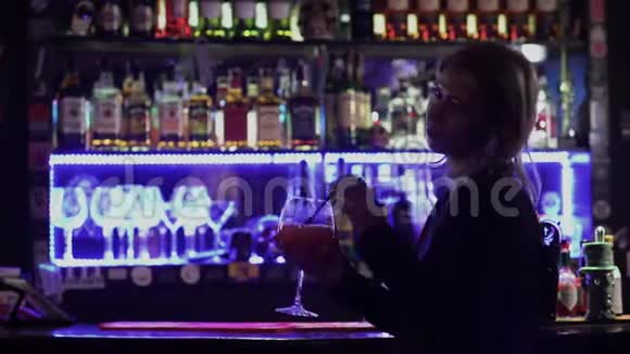 一个金发美女站在酒吧柜台附近背景是夜总会里闪烁的灯光可爱视频的预览图