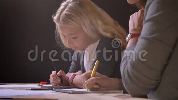 母亲的特写镜头给她漂亮的小女孩上了一课并帮助她做了背景隔离的家庭作业视频的预览图