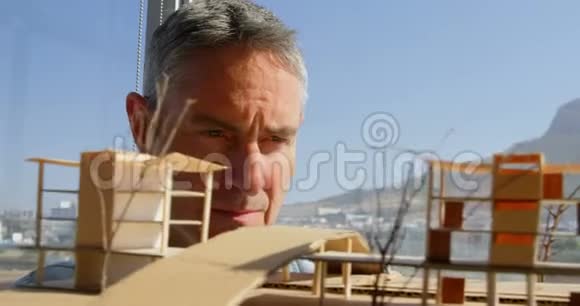 高加索男性建筑师在办公室4k中的建筑模型的正面观察视频的预览图