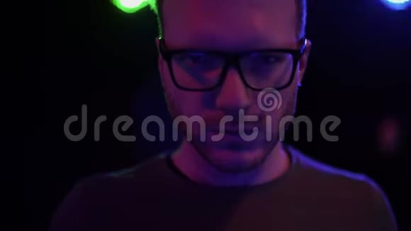 一幅戴眼镜的英俊胡子男站在夜总会灯光闪烁的背景上的肖像视频的预览图