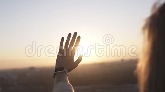戴着智能手表的女人站在屋顶上用手触摸阳光遮住美丽的天空背景快乐视频的预览图