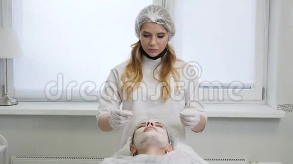 女美容师在躺着的病人身上戴透明胶卷视频的预览图