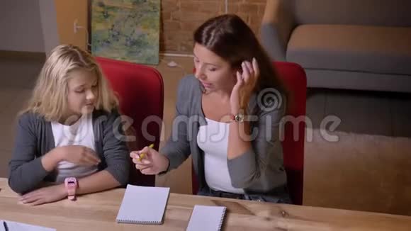 一位年轻的白种人妇女教她漂亮的金发小女孩帮她做家庭作业视频的预览图